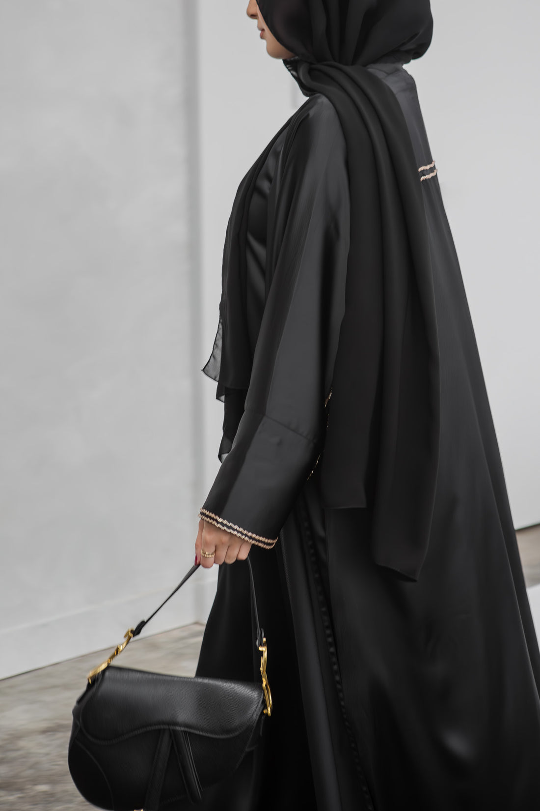 black open abaya with handwork along the sleeve styled with a black handbag